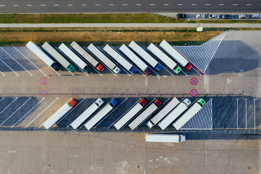 Two rows of 18-wheel trucks in a parking lot.