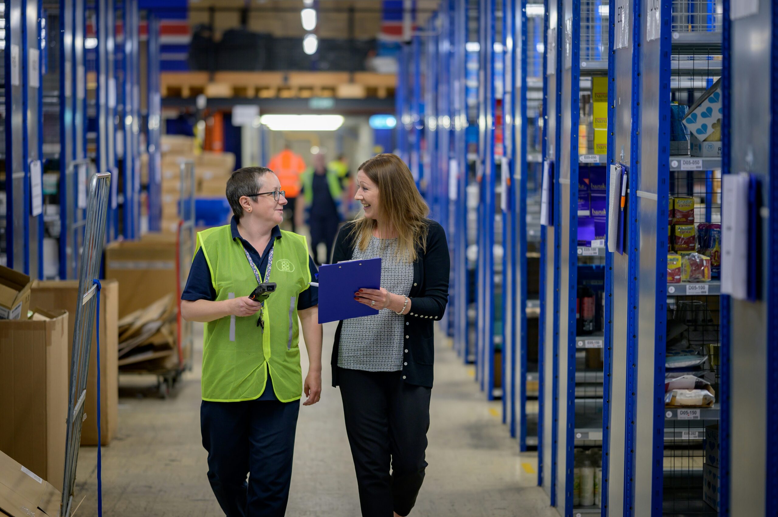 Two logistics professionals walking through a warehouse and talking about dry storage solutions.