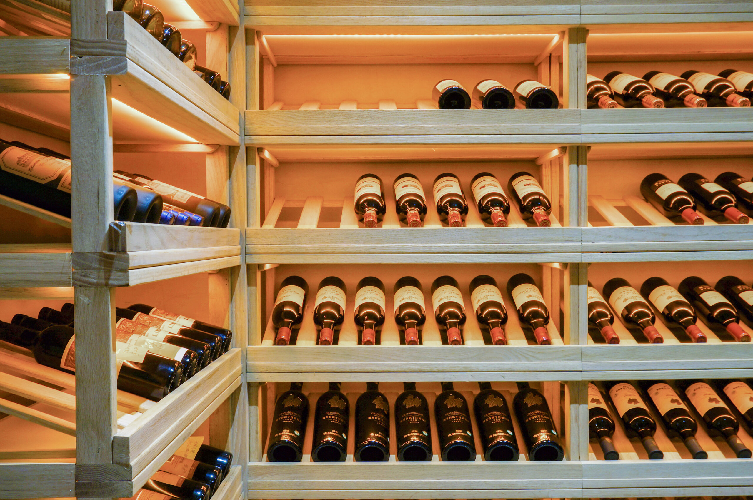 Wooden wine racks filled with red wine bottles in a climate-controlled cellar, representing a valuable collection ready for professional wine relocation services from Mitchell’sNY Logistics.