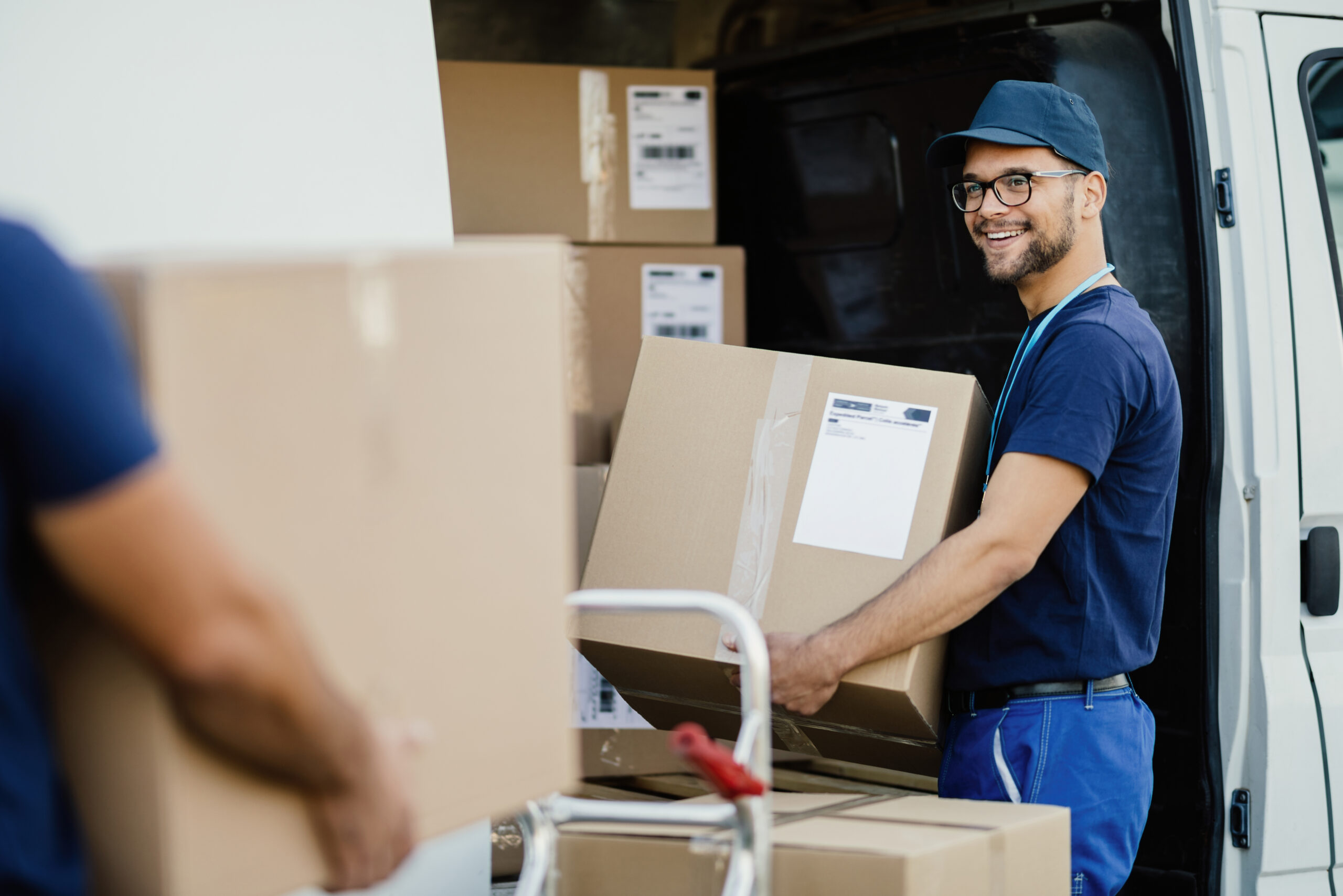Delivery person talking with coworker while loading boxes in a truck.
