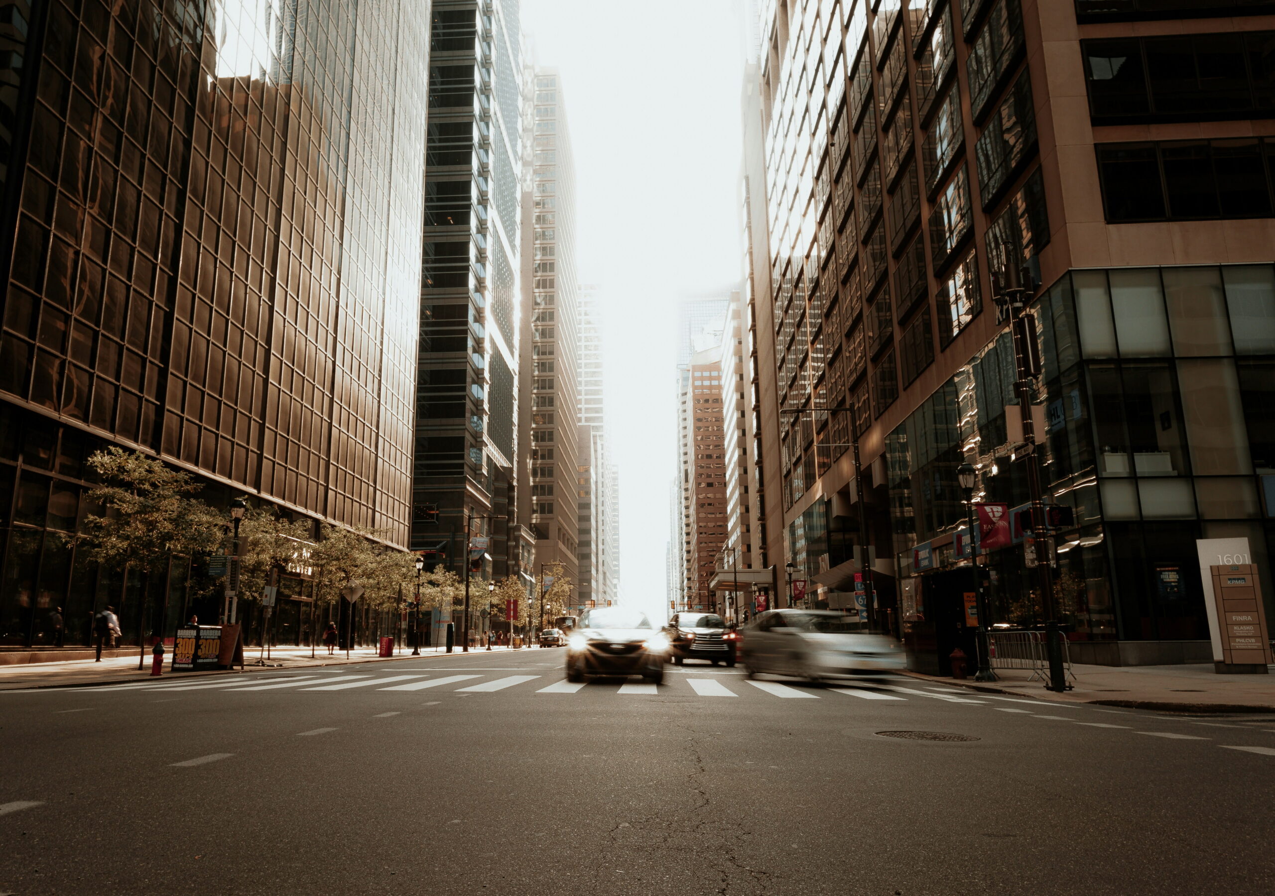 Street-level view of downtown Philadelphia with traffic moving between high-rise office buildings, representing fast-paced business and logistics activity in the city.